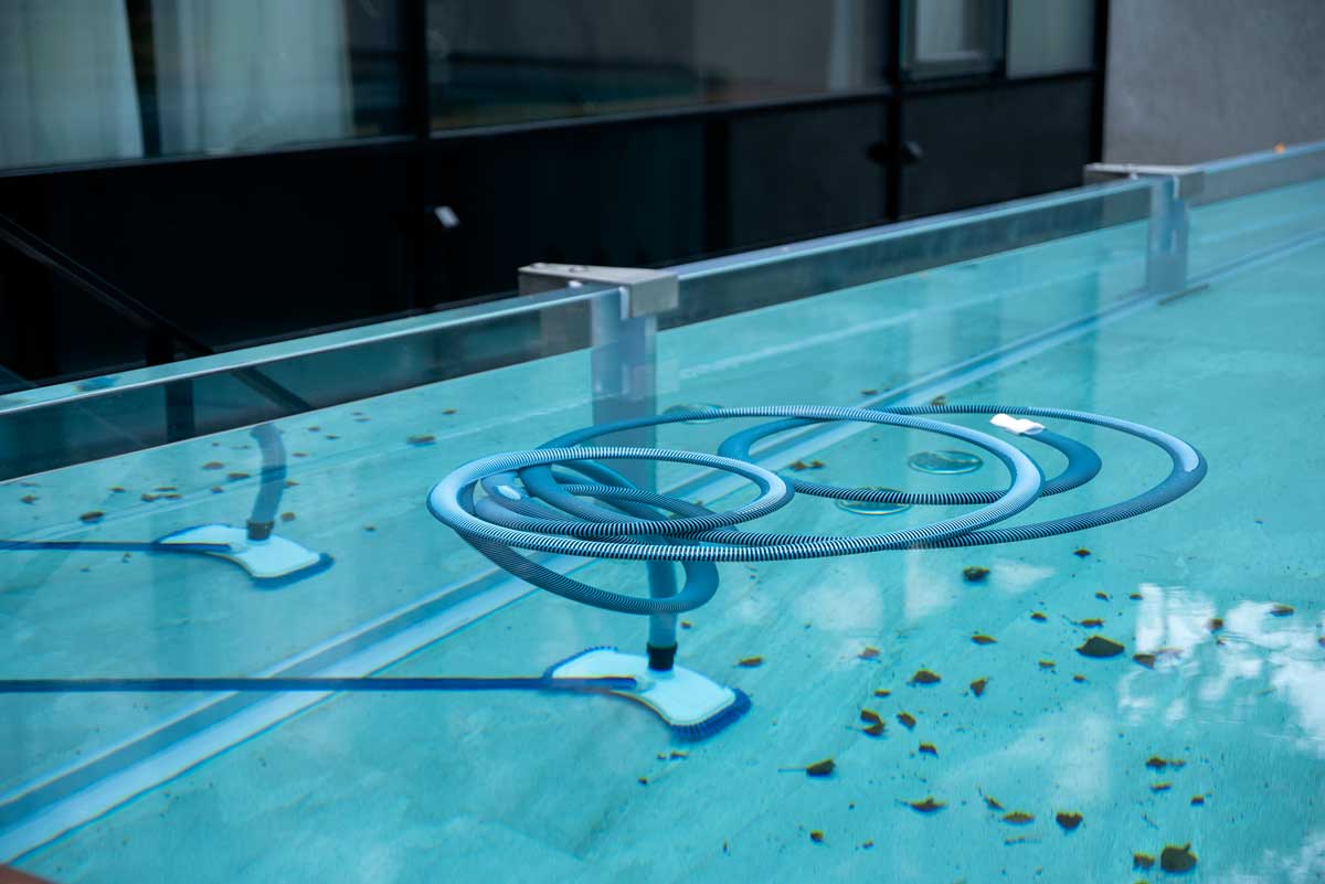 Mătură de curățare scufundată în apa piscinei exterioare, pentru curățarea fundului și a pereților piscinei pline de frunze și alte semne de neglijență - murdărie