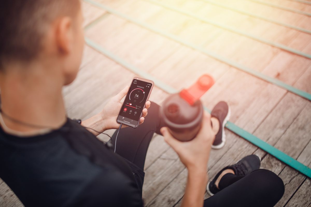 atlet care ține o sticlă de apă și un telefon