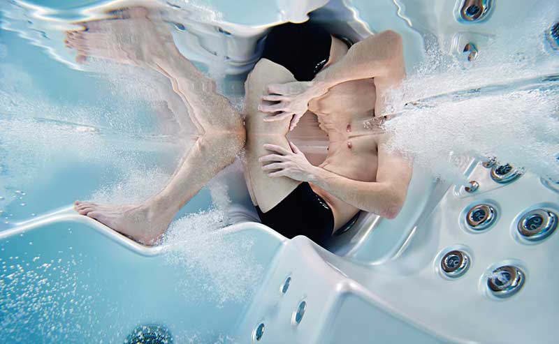 Femeie relaxându-se pe un șezlong ergonomic al unei piscine spa USSPA cu jeturi de hidromasaj în funcțiune